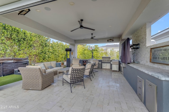 view of patio / terrace featuring a hot tub, an outdoor kitchen, a ceiling fan, a grill, and an outdoor living space