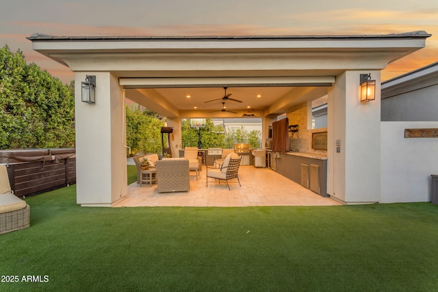 patio terrace at dusk featuring a ceiling fan, outdoor lounge area, a yard, and area for grilling