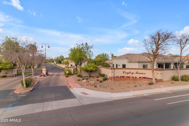 view of street featuring sidewalks, curbs, a gated entry, and street lights