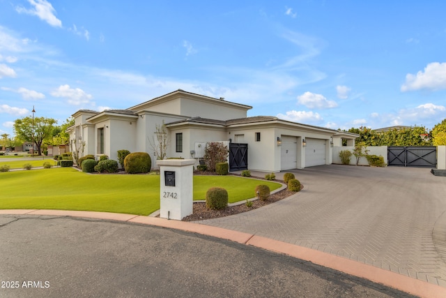 view of front of house with a garage, decorative driveway, a gate, stucco siding, and a front lawn