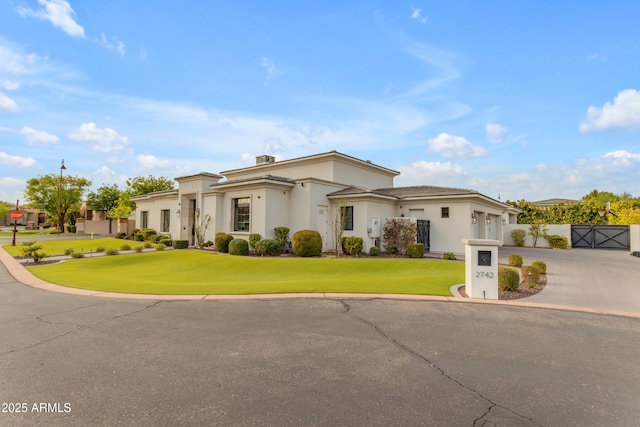 mediterranean / spanish-style home with a front yard, concrete driveway, fence, and stucco siding