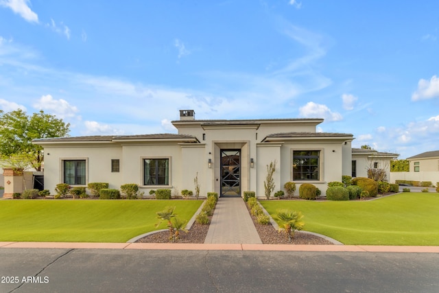 prairie-style house with a chimney, a front lawn, and stucco siding