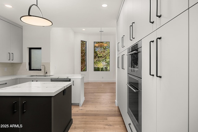 kitchen with pendant lighting, stainless steel oven, a center island, and sink