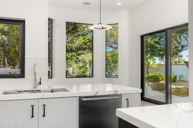 kitchen featuring sink, white cabinetry, light stone countertops, decorative light fixtures, and stainless steel dishwasher