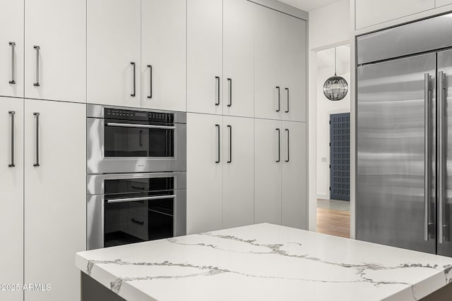 kitchen featuring light stone countertops, appliances with stainless steel finishes, and white cabinets