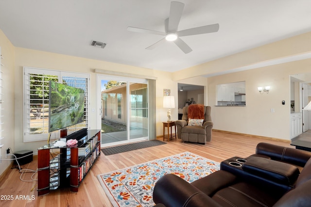 living area with visible vents, ceiling fan, baseboards, and wood finished floors