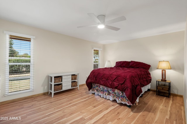 bedroom with a ceiling fan, wood finished floors, and baseboards