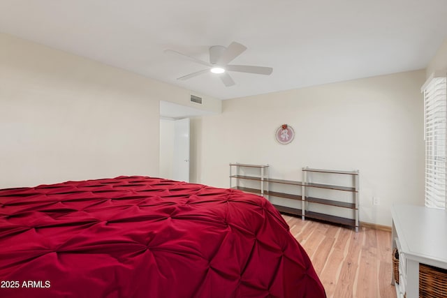 bedroom with visible vents, baseboards, wood finished floors, and a ceiling fan