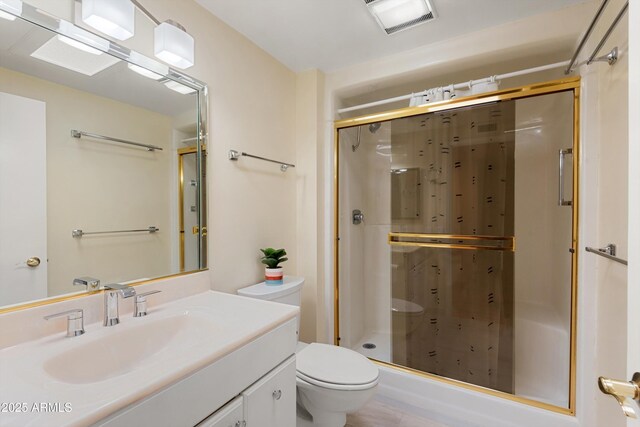 full bathroom with vanity, a shower stall, toilet, and visible vents