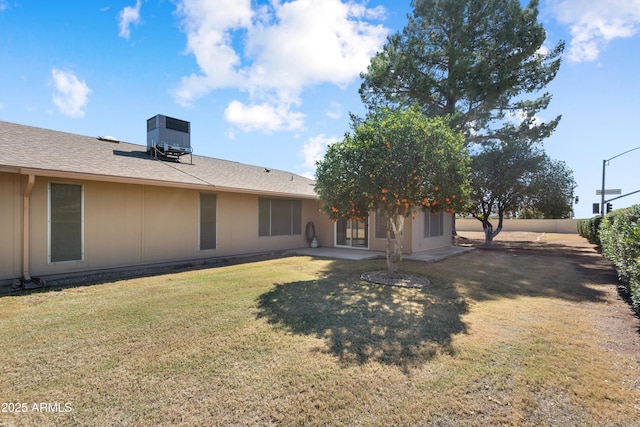 rear view of property with central air condition unit, a lawn, roof with shingles, and fence