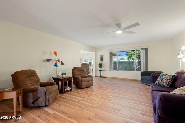 living area with baseboards, light wood-style floors, and ceiling fan