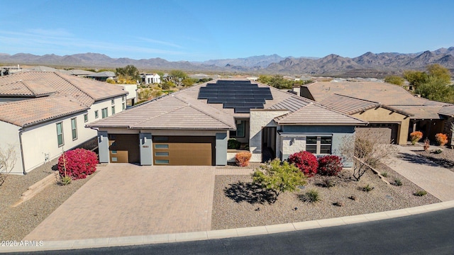 ranch-style house featuring a mountain view, solar panels, and a garage