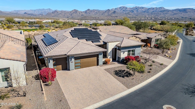 view of front of property featuring a garage, solar panels, and a mountain view