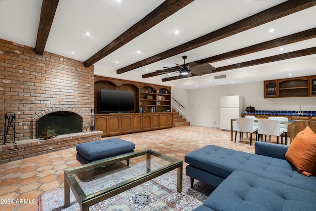 living room with ceiling fan, sink, beamed ceiling, and a brick fireplace