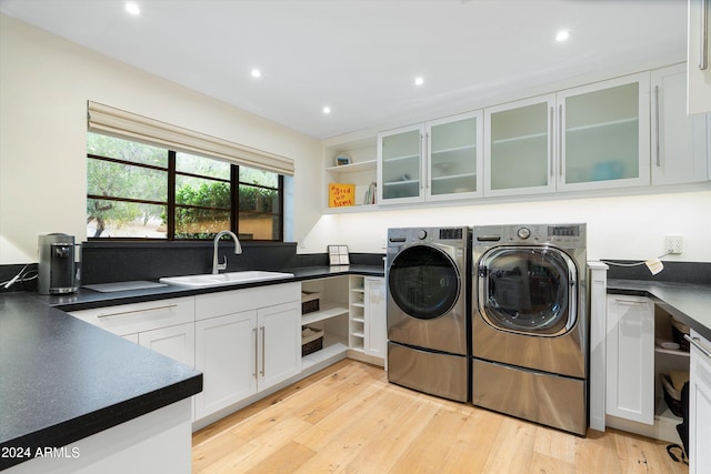 washroom featuring washer and dryer, light hardwood / wood-style floors, cabinets, and sink