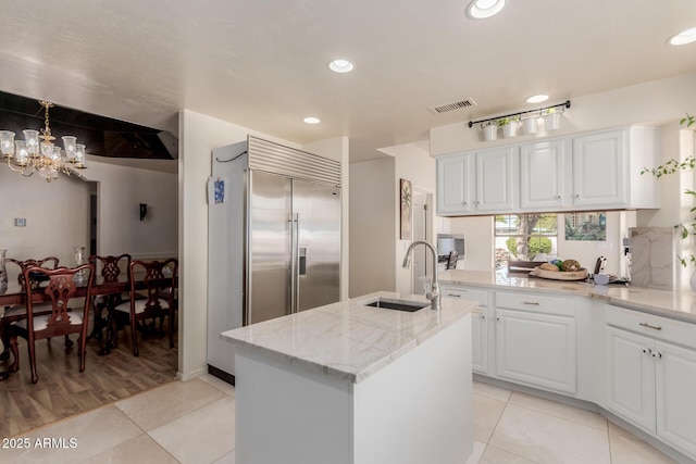 5237 N 106th Ave, Glendale, AZ 85307 - kitchen featuring light tile patterned floors, a chandelier, light stone countertops, built in refrigerator, and white cabinets