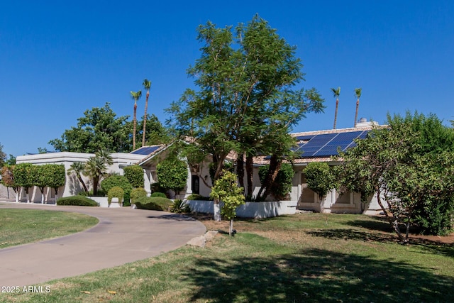 5237 N 106th Ave, Glendale, AZ 85307 - obstructed view of property featuring roof mounted solar panels, a front lawn, curved driveway, and stucco siding
