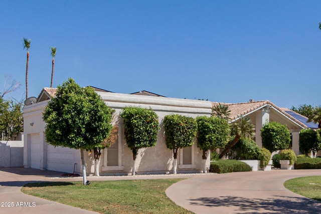 5237 N 106th Ave, Glendale, AZ 85307 - view of property hidden behind natural elements with curved driveway, stucco siding, an attached garage, and a tiled roof