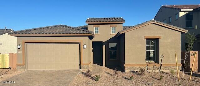 mediterranean / spanish house featuring concrete driveway, a tile roof, an attached garage, fence, and stucco siding