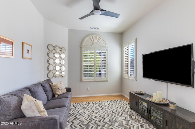 living room with baseboards, light wood-style flooring, visible vents, and a ceiling fan