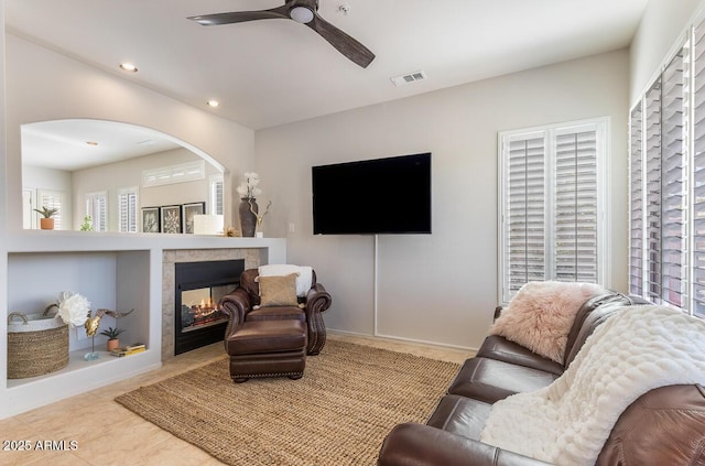 living area featuring baseboards, visible vents, a ceiling fan, a multi sided fireplace, and recessed lighting