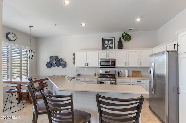 kitchen featuring a sink, white cabinets, light countertops, appliances with stainless steel finishes, and pendant lighting