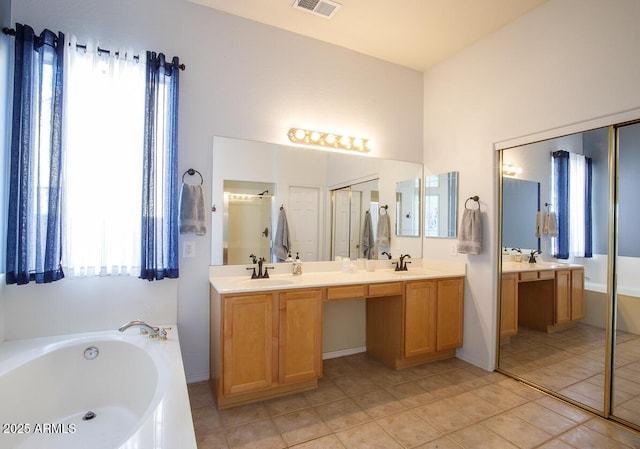 bathroom featuring visible vents, double vanity, a sink, and a bath