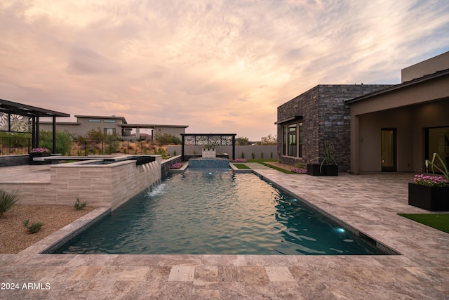 pool at dusk with an in ground hot tub, pool water feature, and a patio