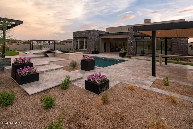 pool at dusk with a patio and an in ground hot tub