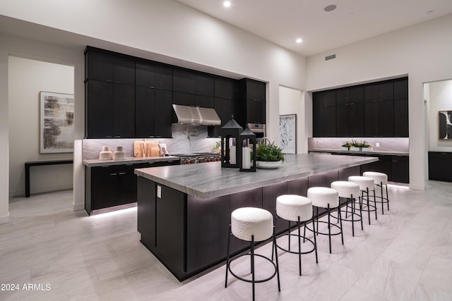 kitchen featuring a large island with sink, tasteful backsplash, stove, and a breakfast bar