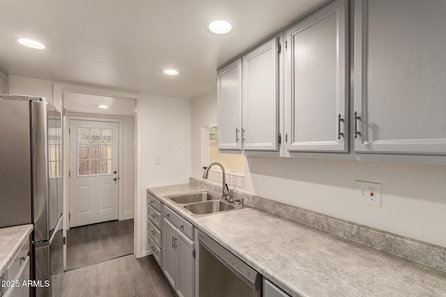 kitchen featuring stainless steel appliances, a sink, dark wood finished floors, light countertops, and recessed lighting