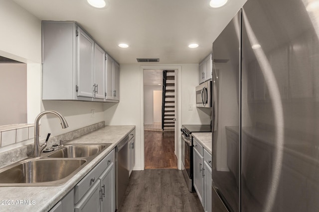 kitchen featuring appliances with stainless steel finishes, a sink, dark wood-style floors, recessed lighting, and light countertops