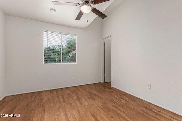 empty room featuring wood finished floors, a ceiling fan, lofted ceiling, a smoke detector, and baseboards