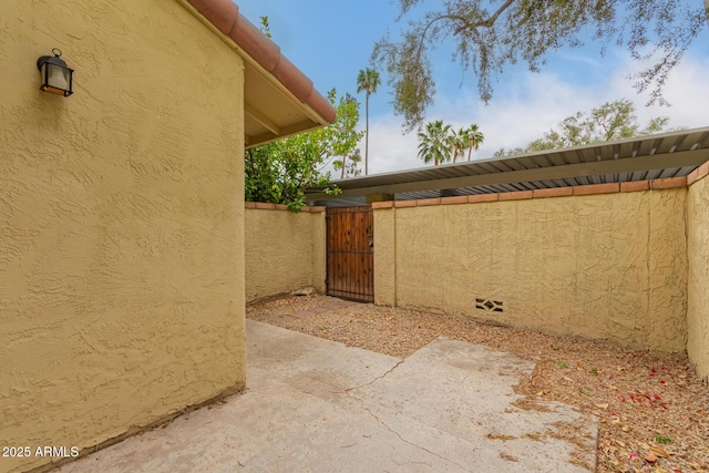 view of side of property with a gate and stucco siding