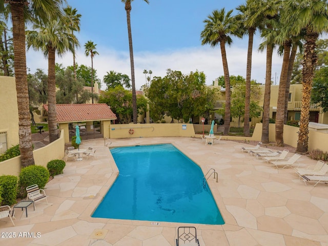 community pool with a patio area and fence