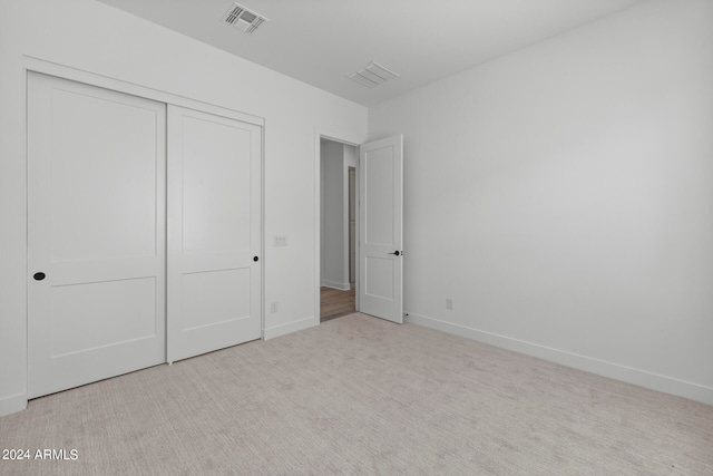 unfurnished bedroom featuring a closet and light colored carpet