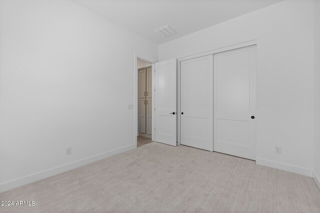 unfurnished bedroom featuring a closet and light colored carpet