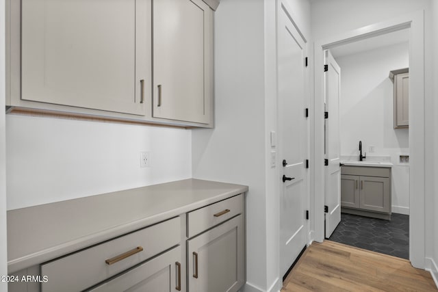 bar featuring light hardwood / wood-style floors, sink, and gray cabinetry