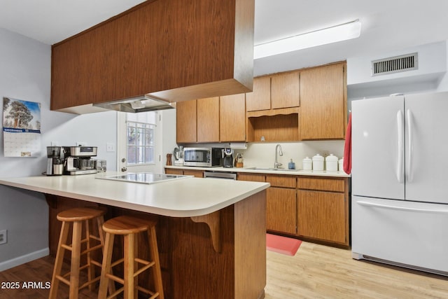 kitchen featuring white refrigerator, sink, black electric cooktop, and kitchen peninsula