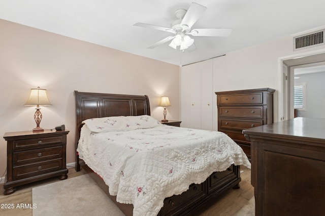 bedroom with ceiling fan, light wood-type flooring, and a closet