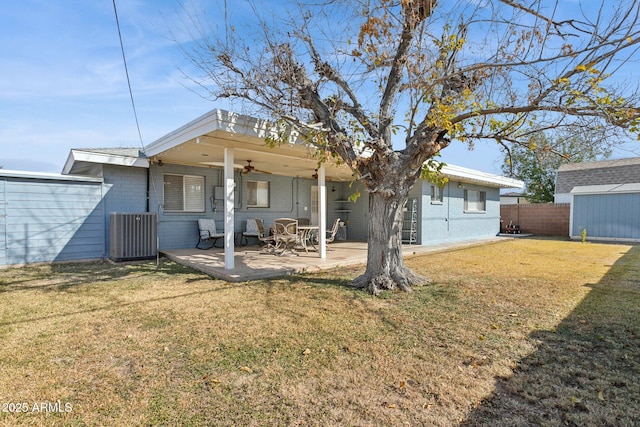 back of property with ceiling fan, a yard, a storage unit, and a patio