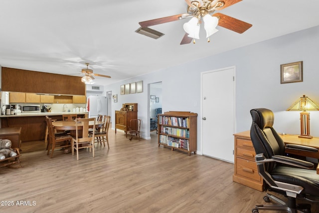 office space featuring ceiling fan, sink, and light wood-type flooring