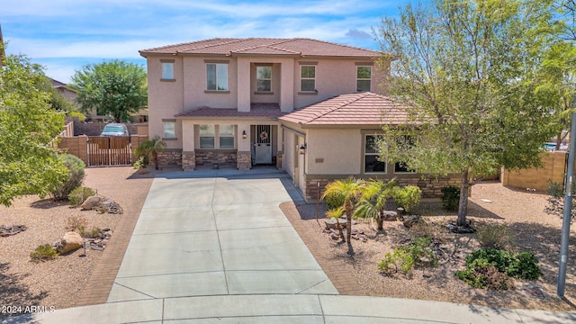 view of front of property featuring fence, driveway, stucco siding, stone siding, and a tiled roof