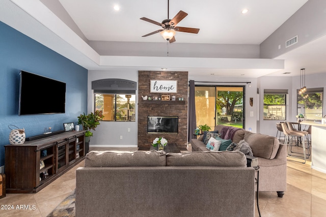 tiled living room featuring lofted ceiling, ceiling fan, and a large fireplace