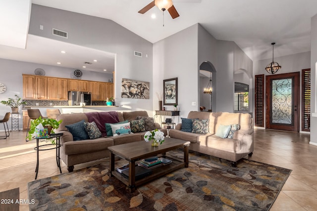 living room featuring light tile patterned flooring, ceiling fan with notable chandelier, and high vaulted ceiling