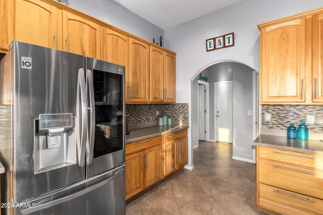 kitchen with stainless steel fridge with ice dispenser, decorative backsplash, and dark tile patterned flooring