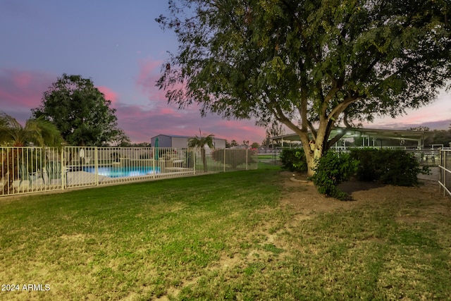 yard at dusk featuring a fenced in pool