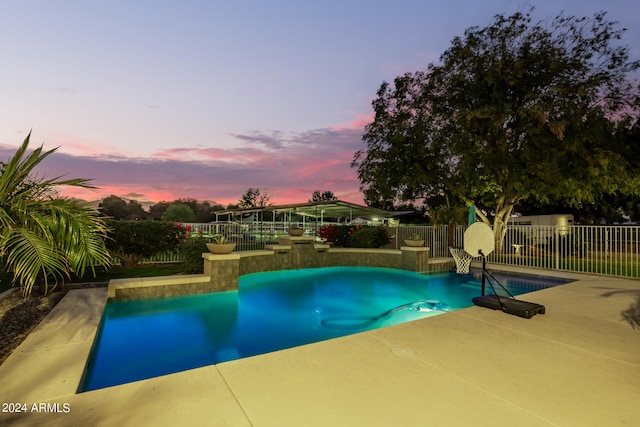 pool at dusk with a patio area