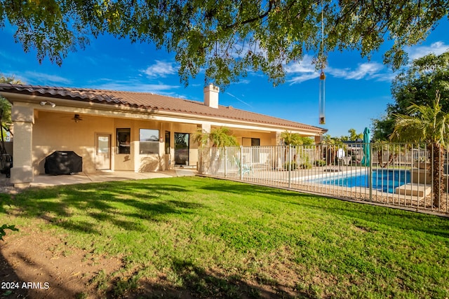 back of property featuring a yard, a patio, and a fenced in pool