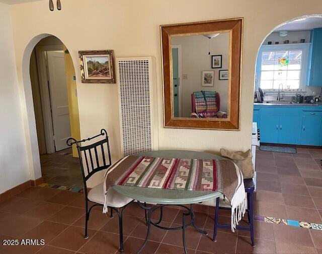 dining space with dark tile patterned floors and arched walkways